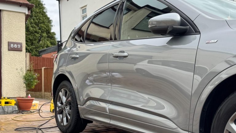 Close-up of a parked white car with a shiny surface on a residential street.